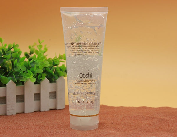 Skincare tube labeled 'Obshi' on a textured surface with a plant in the background
