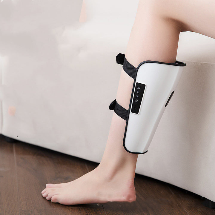 Person using a white and black leg massager on a wooden floor.