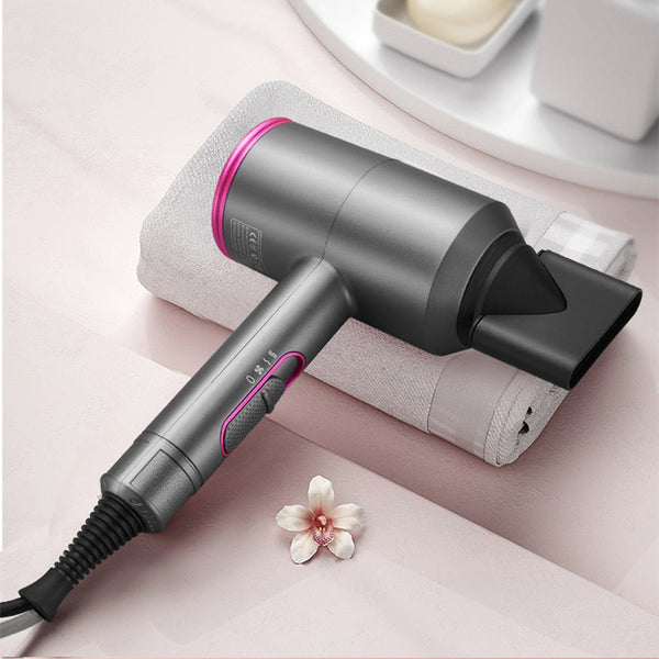 Gray hair dryer with pink accents on a light pink surface with a flower.