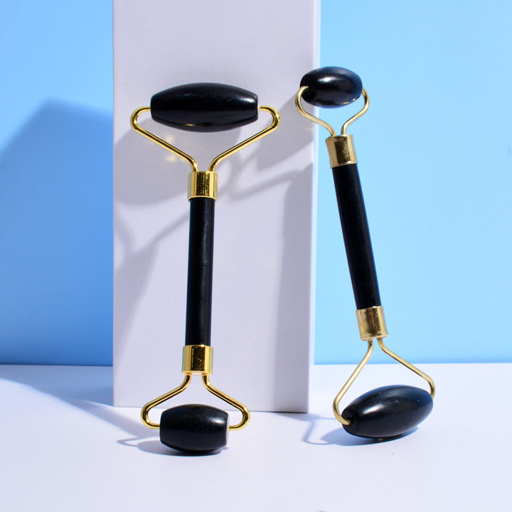 Two black and gold facial rollers on a white and blue background