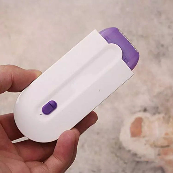 Hand holding a white and purple electronic device on a neutral background